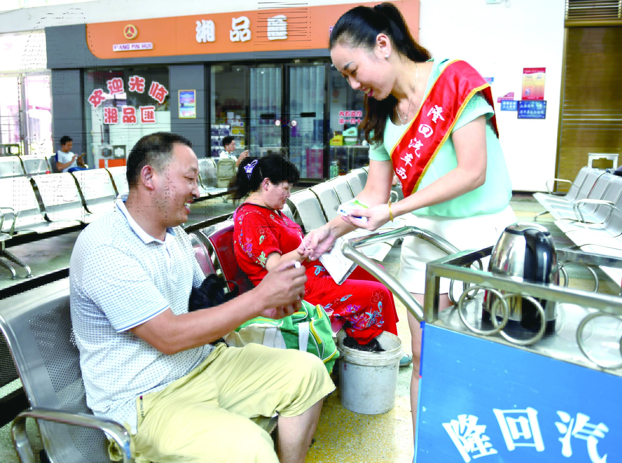 隆回分公司汽車西站工作人員正在為旅客免費(fèi)贈送藿香正氣水。